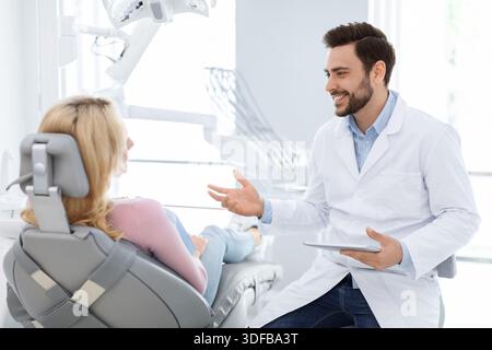Dentista di sesso maschile che mostra la radiografia del paziente femminile su una compressa digitale Foto Stock