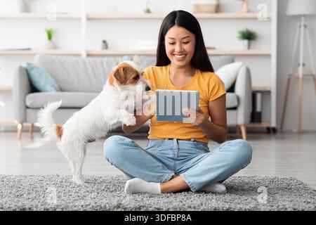 Donna asiatica e cane carino divertirsi insieme a casa Foto Stock