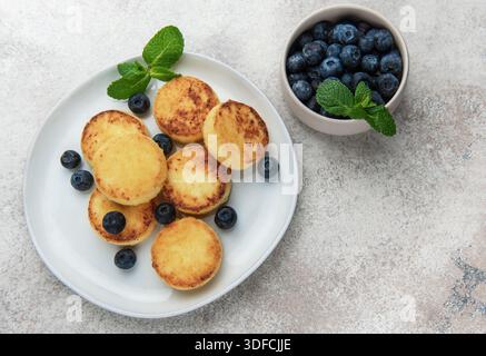 Frittelle di sciroppo dorato con mirtilli freschi e menta per una deliziosa colazione Foto Stock