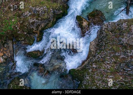 Un affollato torrente di montagna scorre sopra le rocce, creando rapide e acqua bianca. Foto Stock