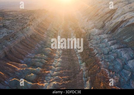 La vista aerea della terra aspra e strutturata, bagnata dalla luce dorata, rivela un paesaggio spettacolare di profondi canyon e formazioni rocciose a strati, Hanksvill Foto Stock