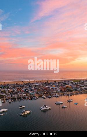 Veduta aerea delle barche ormeggiate nel porto mentre il cielo esplode con le fiammeggianti sfumature del tramonto sulla costa lontana, Newport Beach, California, Stati Uniti Foto Stock