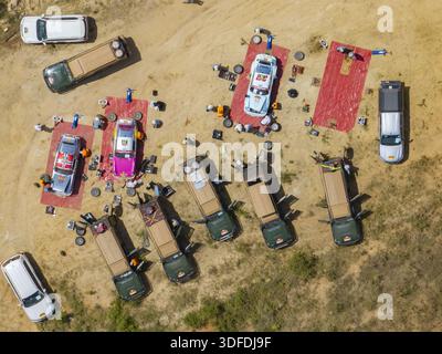 Diani, Kenya - 5 dicembre 2025: Veduta aerea di un pit stop di rally, dove le auto vibranti e i veicoli di supporto creano un suggestivo mosaico contro la sabbia Foto Stock