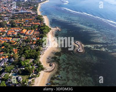 Vista aerea con droni della costa turistica di Sanur Beach, Bali, che mostra ville di lusso, hotel e il turchese Oceano Indiano con una spiaggia unica Foto Stock