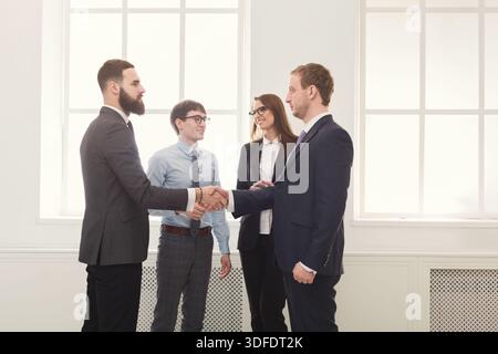 I professionisti aziendali si impegnano in stretta di mano durante le riunioni in un ambiente Office moderno Foto Stock