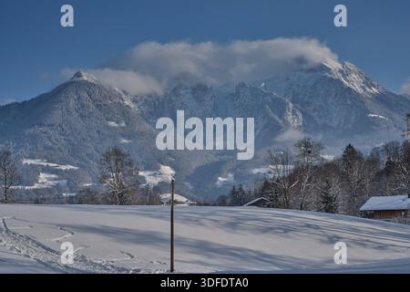 Berchtesgaden, Deutschland 11.01.2026: IM Bild: Verschneite Winterlandschaft mit Blick auf das alpine Bergmassiv. Im Hintergrund sind von links der Kehlstein, der teilweise von Wolken umhüllte Hohe Göll sowie das Hohe Brett zu sehen. Im Vordergrund liegt eine schneebedeckte Wiese mit einzelnen Bäumen und Spuren im Schnee unter klarem Winterhimmel. Bayern *** Berchtesgaden, Germania 11 01 2026 nella foto paesaggio invernale innevato con vista sul massiccio alpino sullo sfondo, il Kehlstein, l'Hohe Göll parzialmente ricoperto di nuvole e l'Hohe Brett si possono vedere da sinistra in Foto Stock