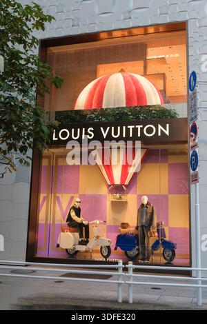Tokyo, Giappone - 09 agosto 2025: Una suggestiva vetrina di Louis Vuitton mostra due scooter e uno sfondo vivace e festoso con una grande striscia Foto Stock