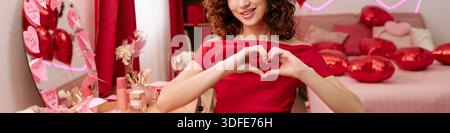 Intestazione di donna sorridente che fa forma a cuore mani in interni Foto Stock