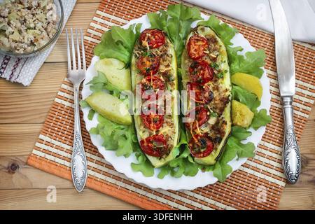 Zucchine su una piastra farcite con carne macinata e verdure con patate e insalata verde. Vista superiore Foto Stock