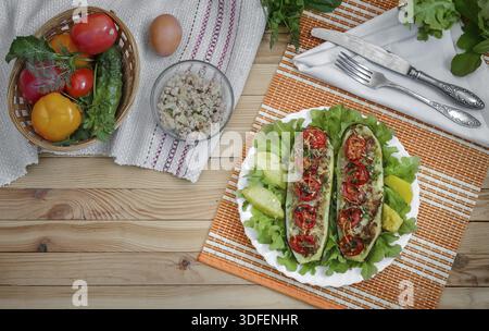 Zucchine su una piastra farcite con carne macinata e verdure con patate e insalata verde. Accanto a loro Foto Stock