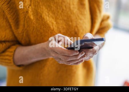 Donna anziana che usa lo smartphone a casa Foto Stock
