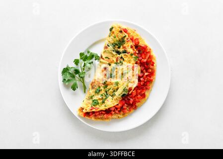 Omelette ripiene con peperone rosso e cipolla verde sul piatto. Vista dall'alto, disposizione piatta Foto Stock