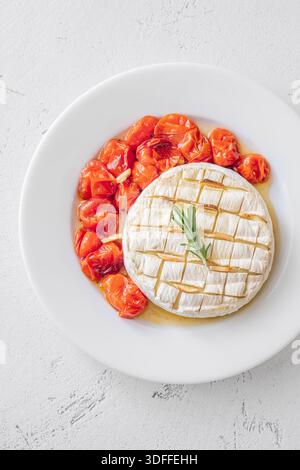 Formaggio cremoso al forno servito con pane tostato e pomodori succosi su sfondo bianco brillante Foto Stock