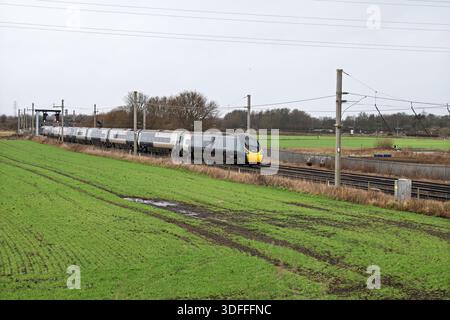 Winwick Junction come Avanti Pendolino si dirige a nord attraverso campi verdi su entrambi i lati dei binari. Foto Stock