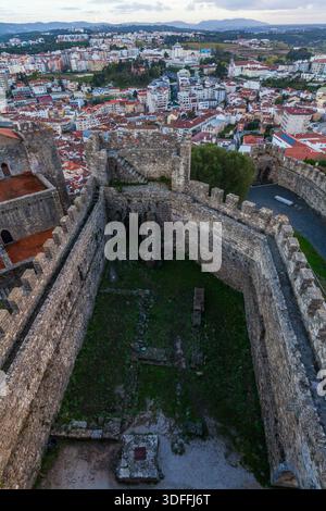 Leiria. Una vista aerea dalla cima delle antiche mura in pietra merlata mostra uno storico cortile del castello che si affaccia su un fitto paesaggio urbano di roo con piastrelle rosse Foto Stock