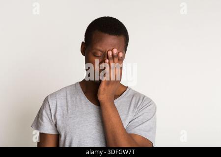 Stanco ritratto di un giovane uomo nero. Mano che copre la faccia Foto Stock