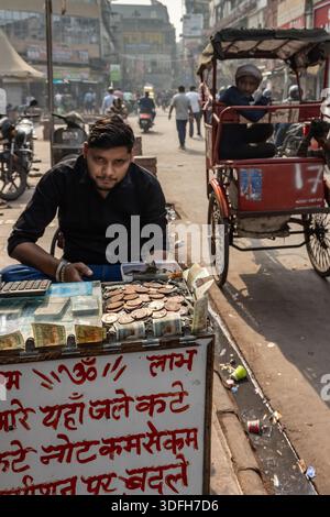 Un venditore ambulante scambia monete danneggiate/vecchie e banconote al mercato Chandni Chowk, a Old Delhi, India. Foto Stock
