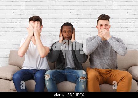 Tre sagge scene di scimmie mostrate da giovani uomini in modo informale Foto Stock
