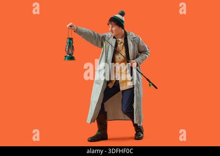Giovane divertente con canna da pesca su sfondo arancione Foto Stock