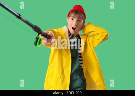 Giovane divertente con canna da pesca su sfondo verde Foto Stock