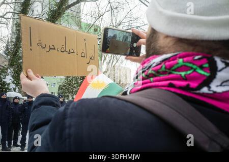 Un manifestante ha un cartello mentre la bandiera nazionale del Kurdistan vola sullo sfondo. Il pomeriggio del 12 gennaio, i manifestanti dei diritti umani si sono riuniti presso l'ambasciata siriana a Varsavia per conto della comunità curda in risposta agli atti di violenza perpetrati contro i civili nei distretti di Aleppo Sheikh Maqsud e al-Ashrafiya. Questi distretti sono stati storicamente abitati dalla comunità curda e sono diventati ancora una volta obiettivi di punizione collettiva contro i civili, compresi bombardamenti e blocchi. (Foto di Neil Milton/SOPA Images/Sipa USA) Foto Stock