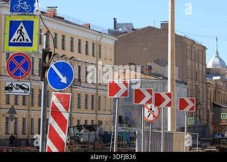 Infrastruttura stradale con diversi cartelli stradali e la direzione di movimento a destra indicata da frecce bianche Foto Stock