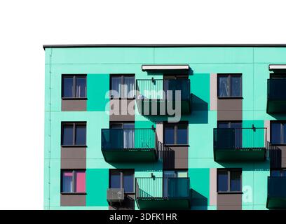 Edificio di appartamenti contemporaneo con una facciata turchese e grigia, balconi in vetro e finestre con cornici scure, isolate su sfondo bianco. resid moderno Foto Stock