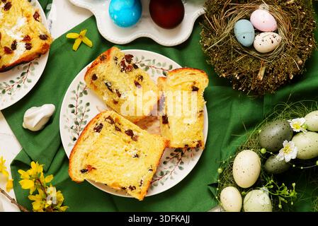 Tradizionale kraffin di pasticceria pasquale con ricotta e uva passa sullo sfondo pasquale e uova dipinte Foto Stock