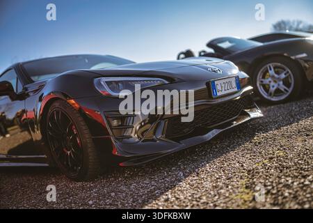 Imola, italia 01 gennaio 2026: toyota gt86 coupé nera parcheggiata su ghiaia sotto il cielo azzurro, vista frontale ribassata che enfatizza la griglia, i fari, la cust Foto Stock