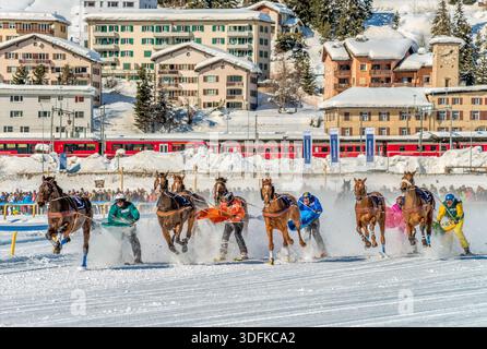 Cavalli e atleti di sci corrono attraverso il lago ghiacciato durante la famosa corsa di cavalli White Turf a St. Moritz, Svizzera Foto Stock