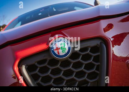 Imola, italia 01 gennaio 2026: Emblema alfa romeo con biscione e croce rossa su griglia rossa lucida per auto sportive, primo piano che mostra il patrimonio italiano e. Foto Stock