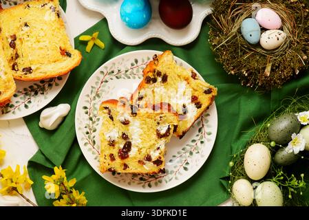 Tradizionale kraffin di pasticceria pasquale con ricotta e uva passa sullo sfondo pasquale e uova dipinte Foto Stock