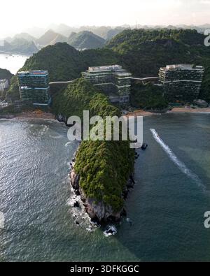 Veduta aerea di edifici moderni annidati in cima a una lussureggiante penisola verde, dove il mare turchese incontra la spiaggia sabbiosa di Trân Châu, hai Phong, Vietnam. Foto Stock