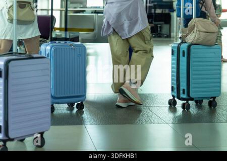 Viaggiatori con valigie rotanti che camminano all'interno di un terminal dell'aeroporto. Concetto di viaggio aereo, trasporto e mobilità dei passeggeri. Foto Stock