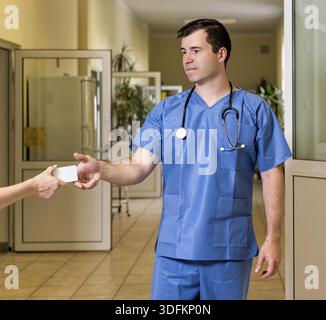 La mezza età, bianco caucasico, maschio medico in frega con uno stetoscopio accettazione carta bianca, ospedale sfocata corridoio in background Foto Stock