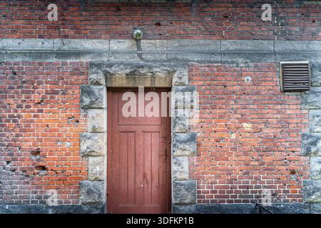 Buchi bullet in una facciata casa dalla seconda guerra mondiale Rustico, muro di mattoni rossi con porte di accademia marittima o università di Szczecin, Polonia Foto Stock