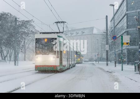 Il tram stradale invernale mostra le forti nevicate dei trasporti pubblici in condizioni di ghiaccio ridotta visibilità. Piste innevate edifici urbani mobilità Foto Stock