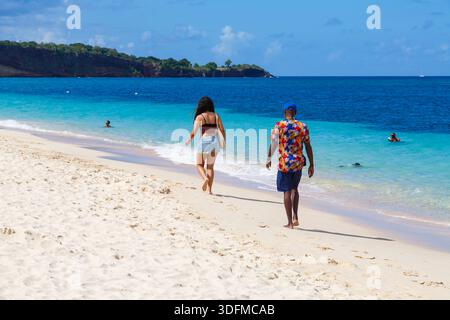 Donna e uomo che camminano lungo la riva del mare sul retro della spiaggia di Grand Anse, Grenada, Isole dei Caraibi a dicembre Foto Stock
