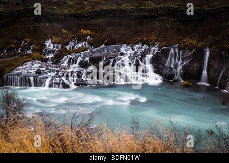 Vista delle acque azzurre lattiginose in contrasto con le rocce vulcaniche scure, mentre le cascate d'acqua sulla cascata di Barnafoss nell'Islanda occidentale, Modruvellir, Islanda occidentale, Foto Stock