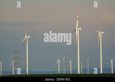 Un'immagine di un'infrastruttura energetica integrata, con un grande parco eolico per la generazione rinnovabile e un pilone di trasmissione ad alta tensione, Illust Foto Stock