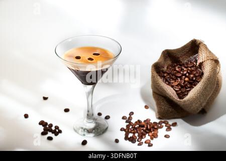 Cocktail espresso martini in un bicchiere con una borsa di caffè torrefatto, suggerendo ingredienti e una bevanda unica Foto Stock
