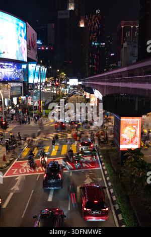 KUALA LUMPUR, MALESIA - 24 FEBBRAIO 2024: Vista dall'alto del traffico pesante e dei pedoni all'incrocio illuminato di Bukit Bintang di notte Foto Stock