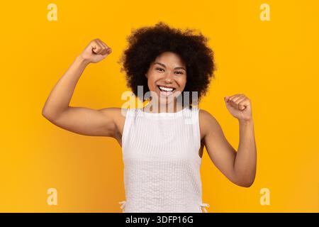 Felice giovane donna afroamericana che celebra il successo con i pugni alzati Foto Stock