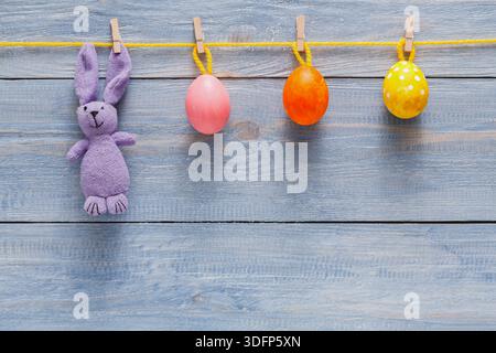 Colorate decorazioni pasquali appese a una corda con un soffice coniglietto e uova dipinte Foto Stock