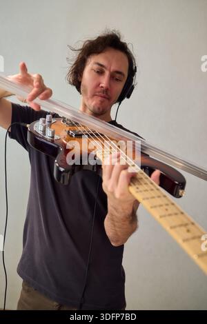 Bassi potenti, prestazioni dinamiche che comunicano con passione attraverso il basso, musicista dai capelli ricci immersi in bassi espressivi Foto Stock