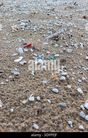 Spiaggia sabbiosa contaminata da microplastiche. Vista ravvicinata di microplastiche e rifiuti su una spiaggia. Foto Stock
