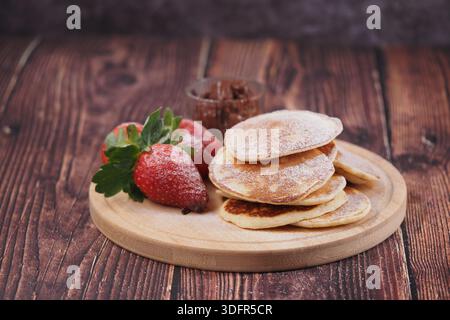Pancake con fragole e cioccolato su legno Foto Stock