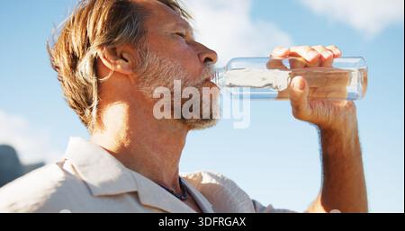 Sotto, uomo maturo e acqua potabile per fitness all'aperto per idratazione, nutrizione e pausa esercizio fisico. Uomo, sete e bottiglia rinfrescante Foto Stock