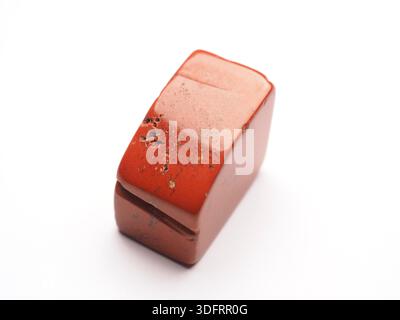 Primo piano di una pietra di guarigione rossa di jasper su sfondo bianco, pietra concettuale di coraggio, forza di volontà e vitalità Foto Stock