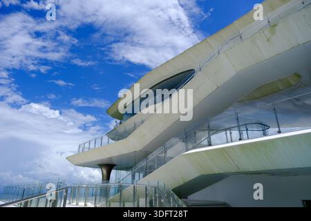 Incredibile vista ad angolo basso di una moderna struttura architettonica a più strati contro un cielo blu spettacolare con nuvole bianche. Foto Stock